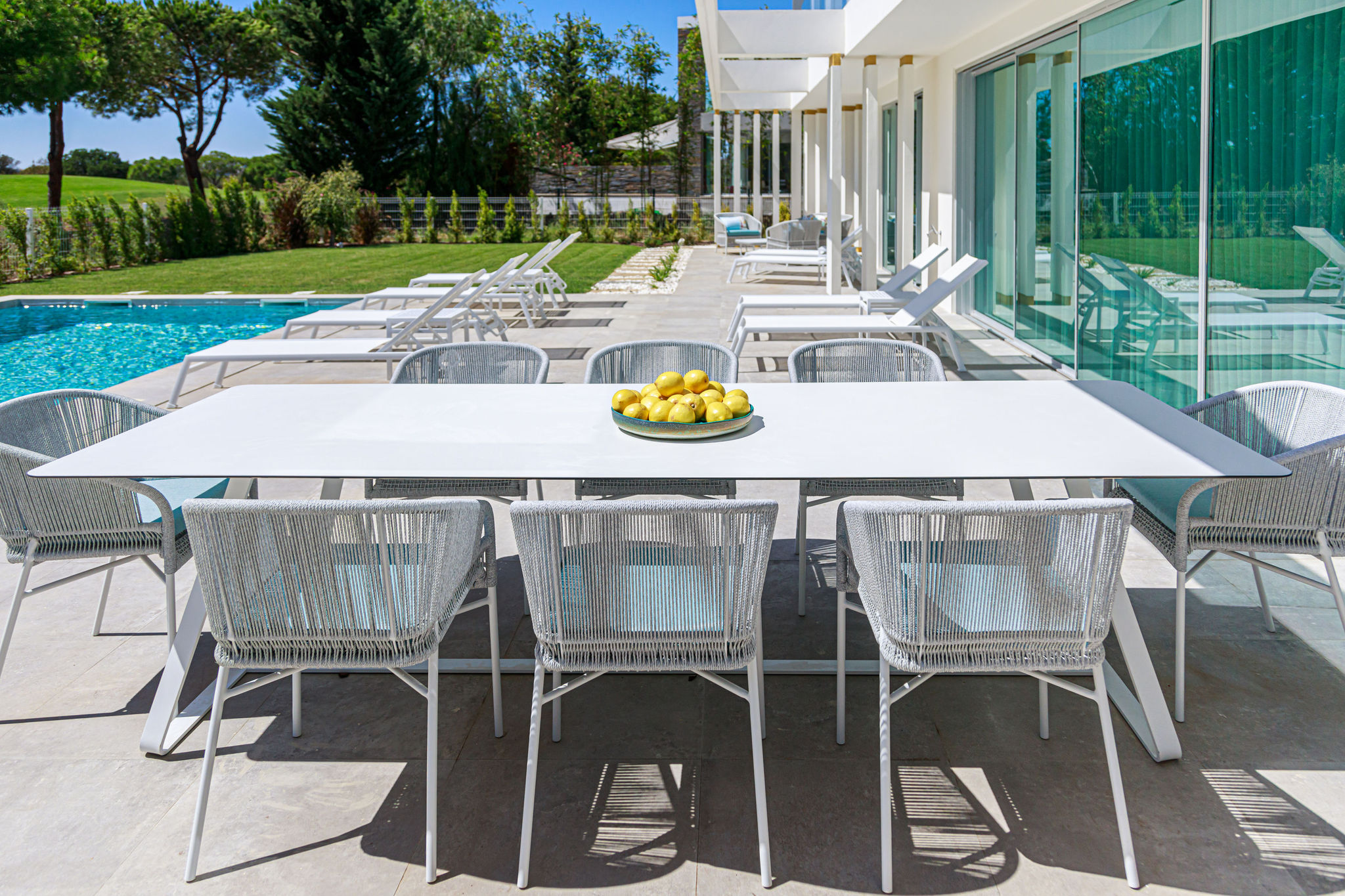 Outdoor dining table and chair set in grey woven material and white surfaces