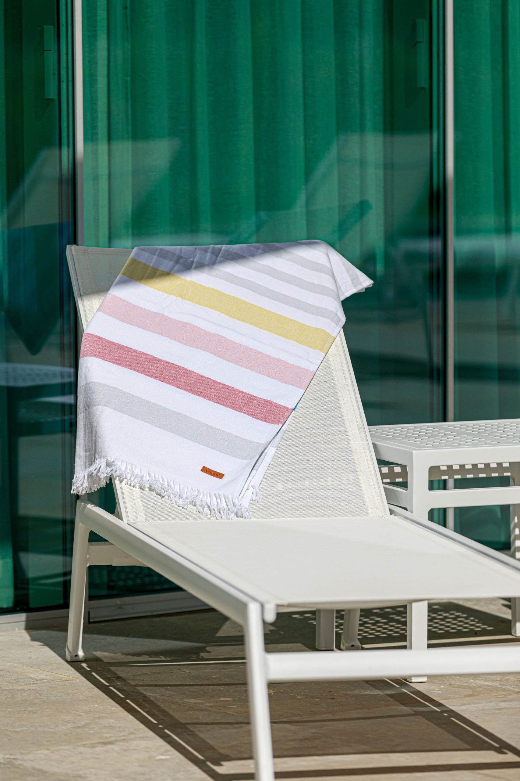 Modern and minimalist outdoor sun lounger with draped striped beach towel