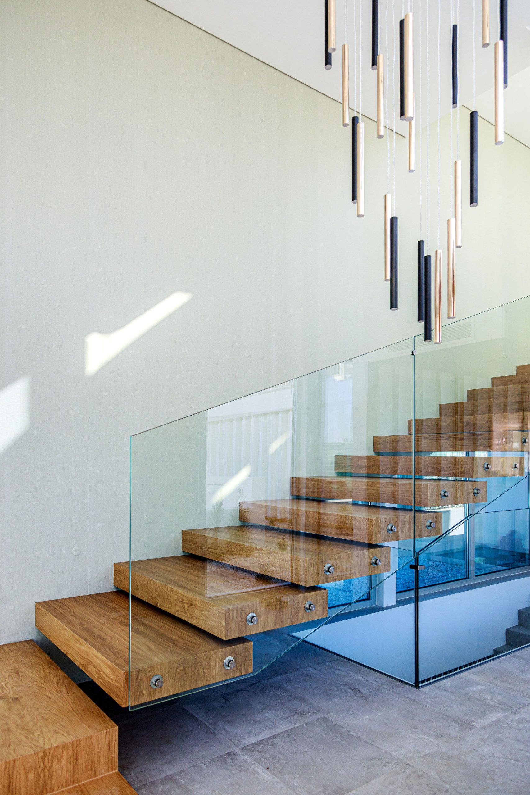 Glass stair case detail against wall-mounted floating wooden stairs